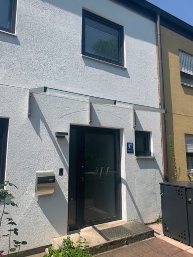 Eingang zu einem modernen Wohnhaus mit weißer Fassade und einem Briefkasten.